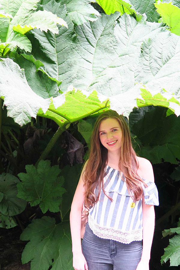 melissa carne standing under giant rhubarb at the lost gardens of heligan in cornwall