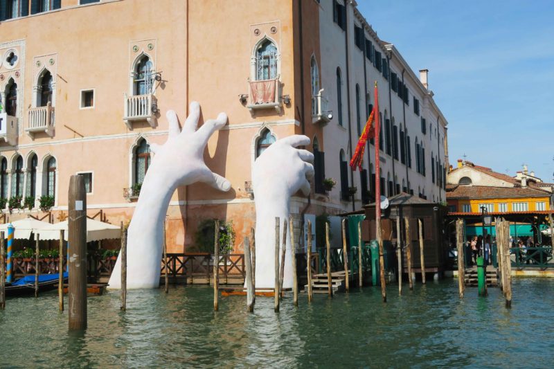 giant hand concrete statue on side of building in venice grand canal in italy