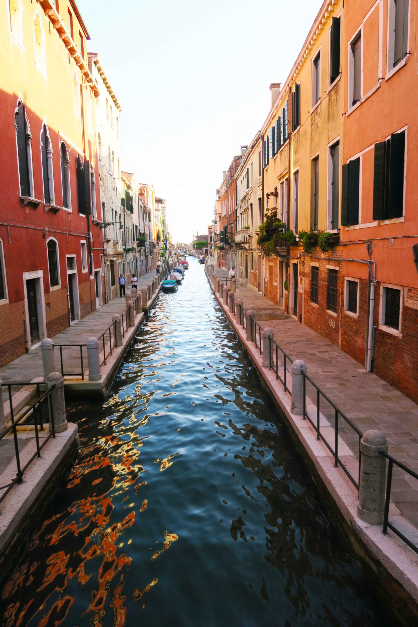 canal with orange houses either side in venice, italy