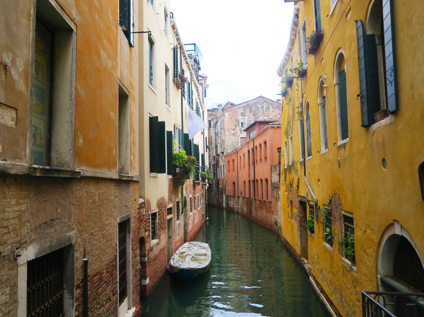 canal in venice with yellow houses