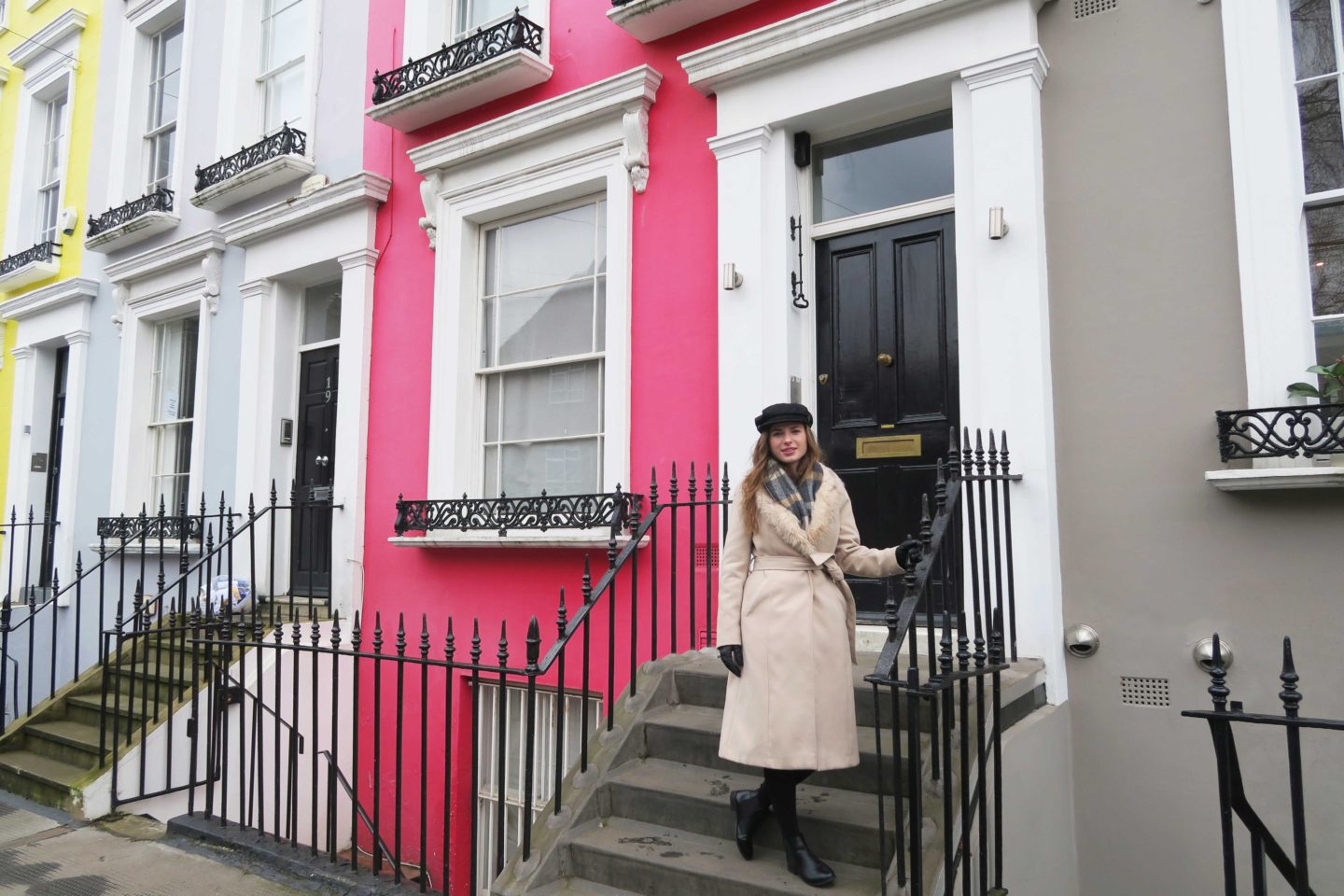 melissa carne standing in front of colourful houses in notting hill in london wearing a baker boy hat