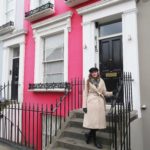 melissa carne standing in front of colourful houses in notting hill in london wearing a baker boy hat