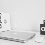 black and white photo of mac book on a graphic designers desk