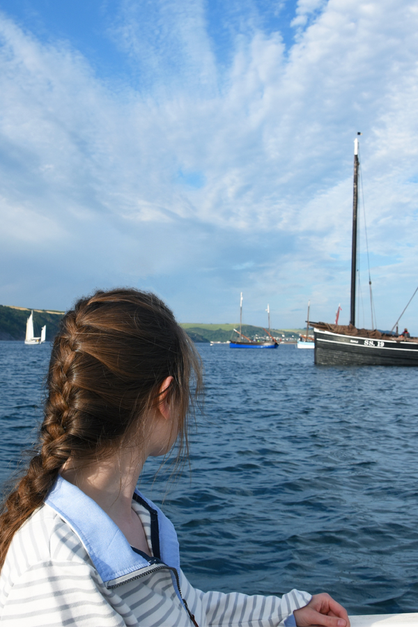 melissa carne wearing a french plait looking at lugger ships in looe in cornwall