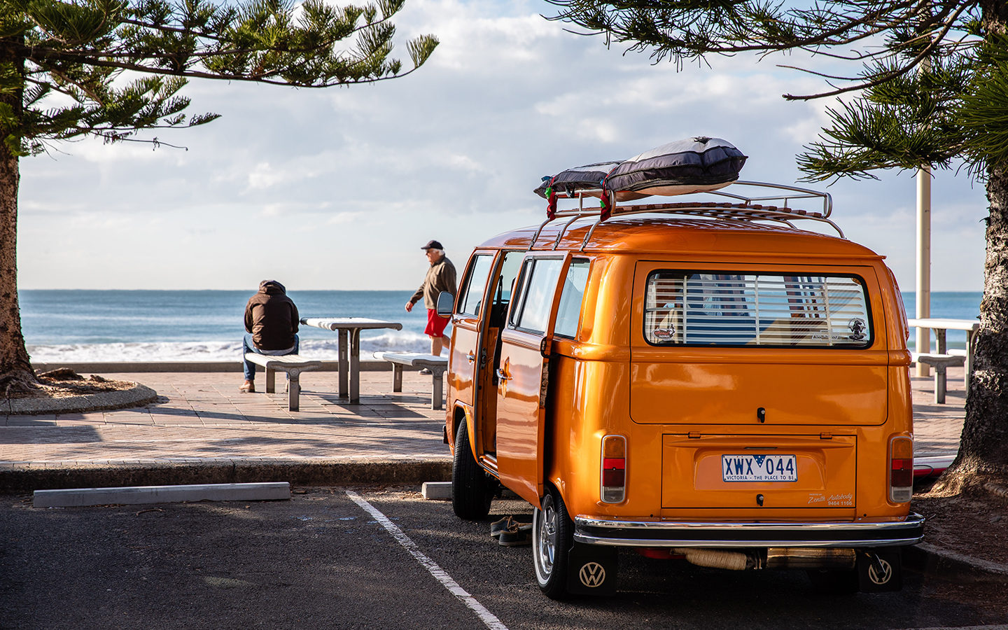 orange camper van parked by beach
