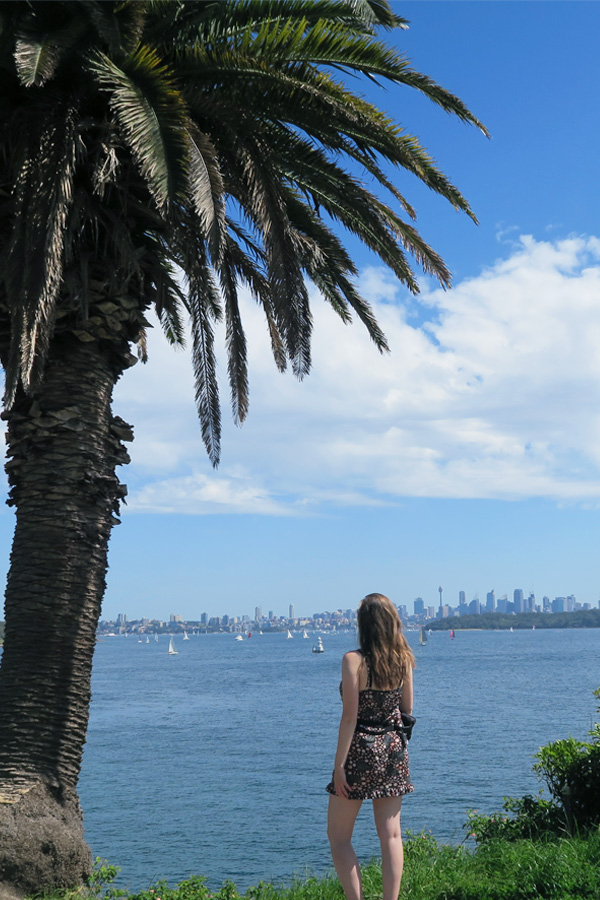 melissa carne standing next t palm tree overlooking sydney harbour in australia