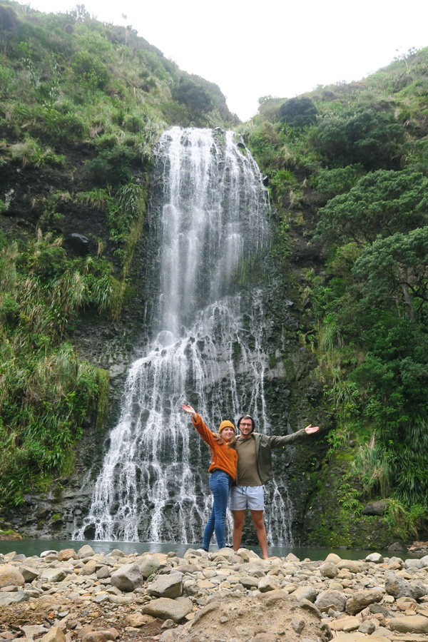 people in front of kare kare waterfall near piha in new zealand