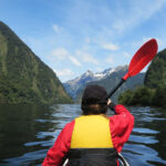 girl kayaking in doubtful sound in new zealand
