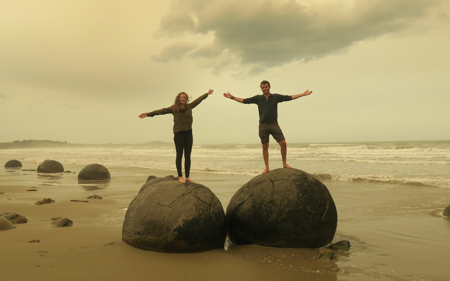couple posing on moeraki boulders in new zealand