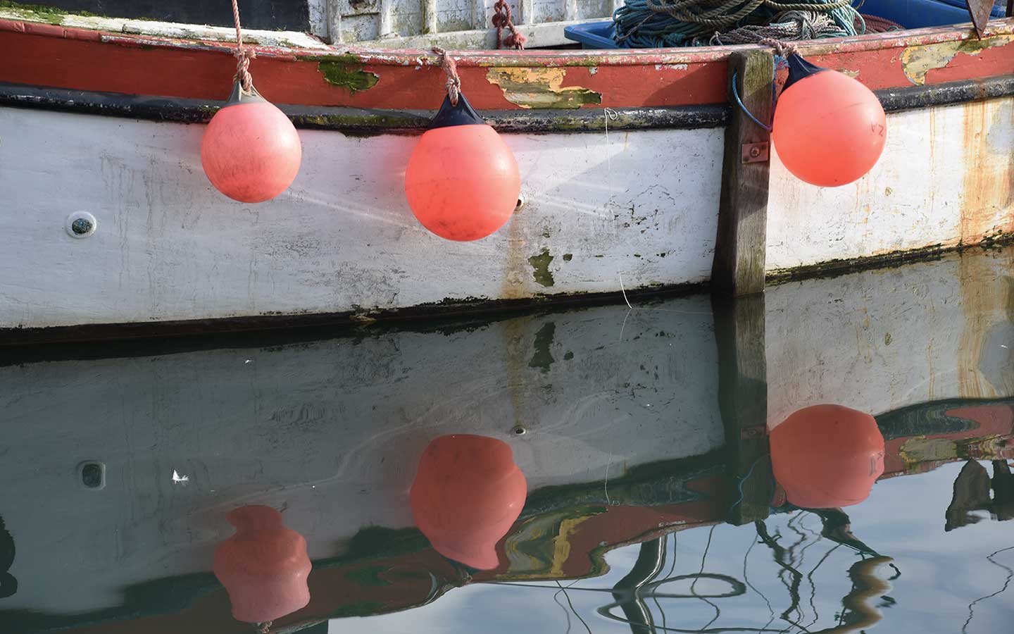 orange buoys on white fishing boat in cornwall