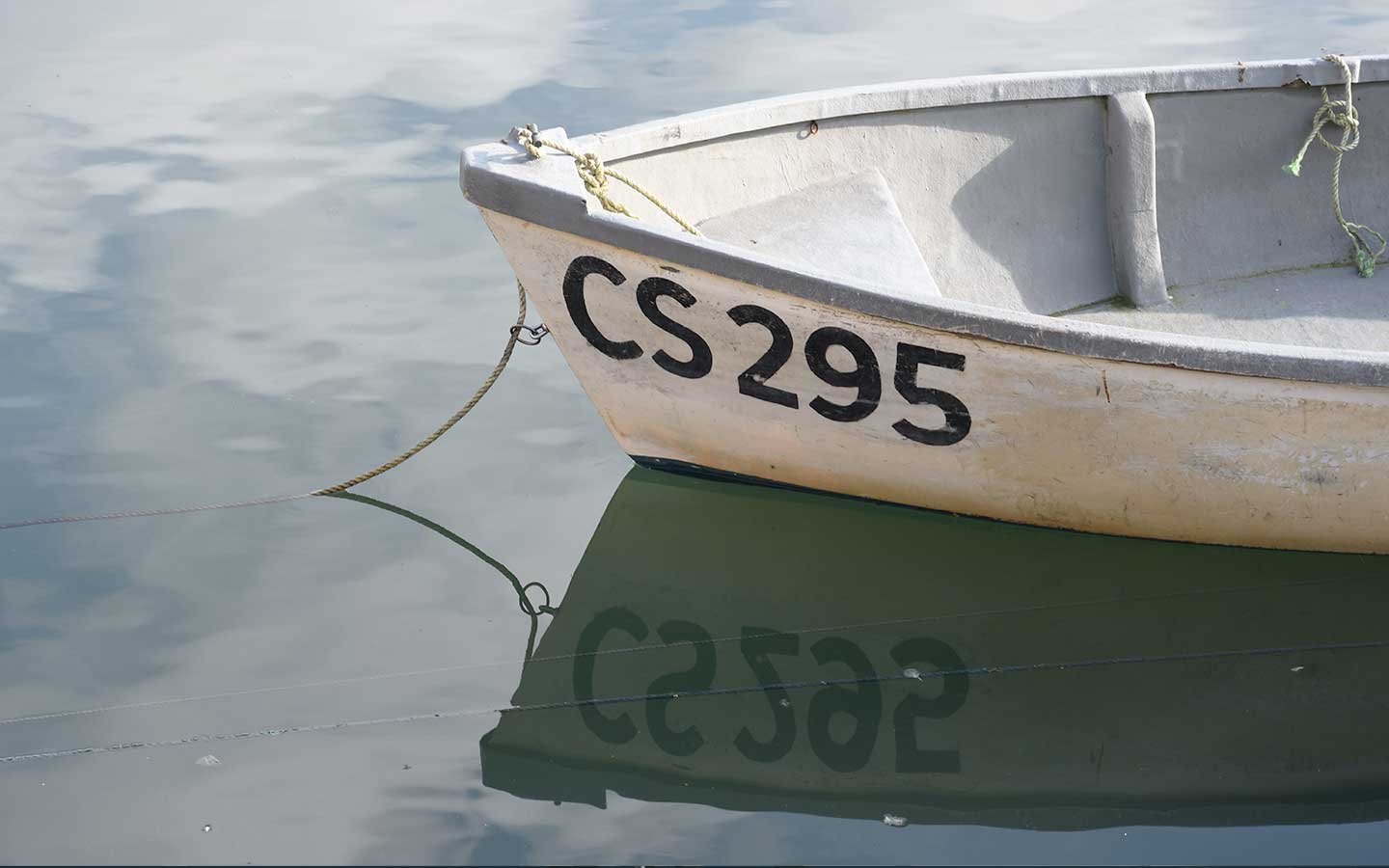 boat with numbers reflecting in the water at mevagissey