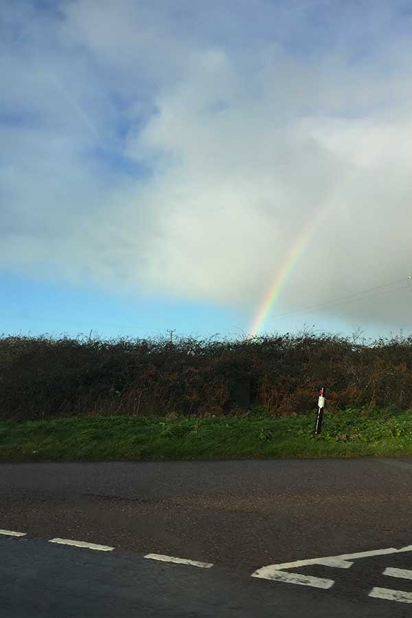 rainbow over cornish countryside road in cornwall